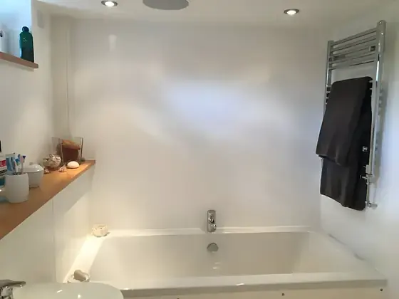 Fulbourn bathroom with white painted walls, built-in bath, timber shelf and heated towel rail