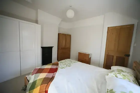 Histon bedroom with white fitted wardrobes, black cast-iron fireplace and stripped pine door