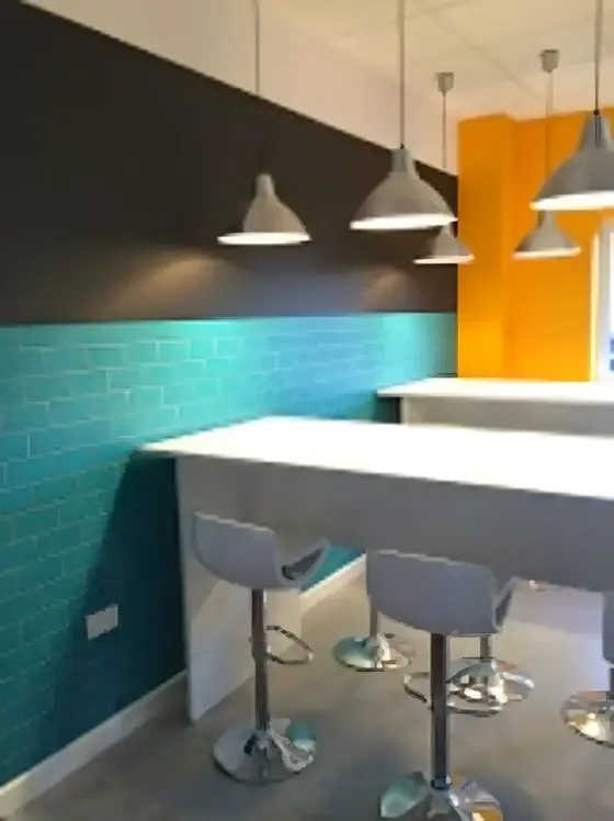 Student kitchen bar in Colchester with teal brick-effect wall, charcoal upper wall and orange feature panel