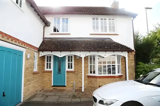 Detached house front with white rendered walls, turquoise front door, turquoise garage door and white window frames