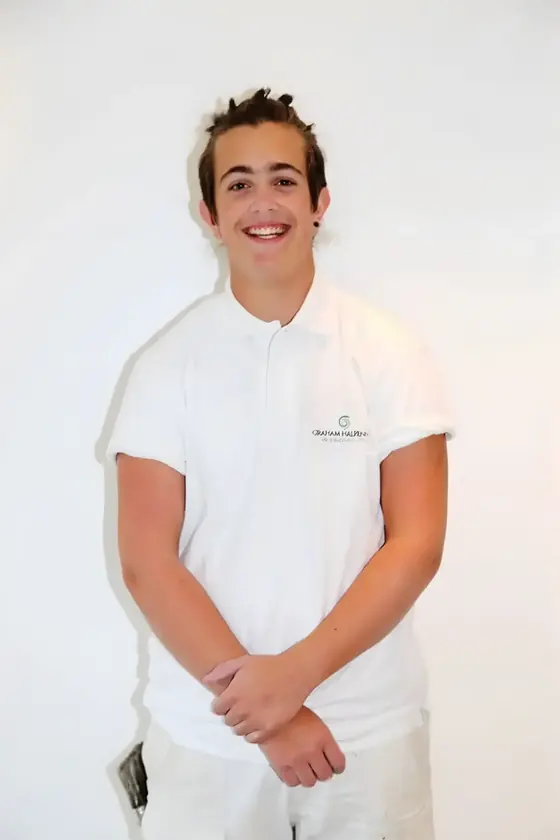 Smiling young decorator in a white polo shirt standing against a white backdrop