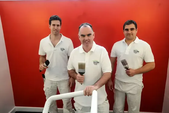 Three Graham Halpenny decorators in branded whites, holding brushes