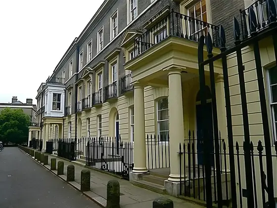 Terrace of cream-painted Georgian townhouses with columned porch and black iron railings