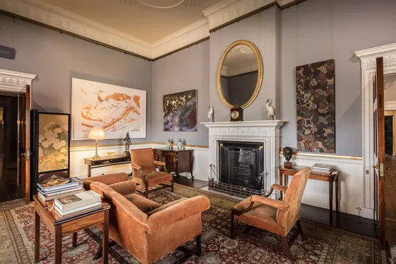 Period sitting room with grey-blue painted walls, white panelling and a carved fireplace
