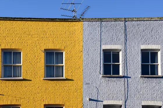 Terrace of brick houses with painted yellow and pale grey facades and white sash windows