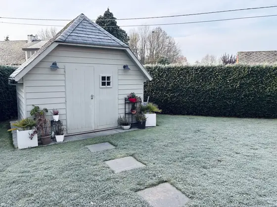 Painted grey garden shed with white double doors on a frosted lawn