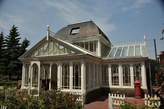 A white Victorian-style conservatory in a garden