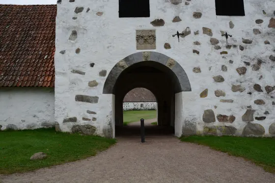 A whitewashed stone gatehouse with a red tiled roof