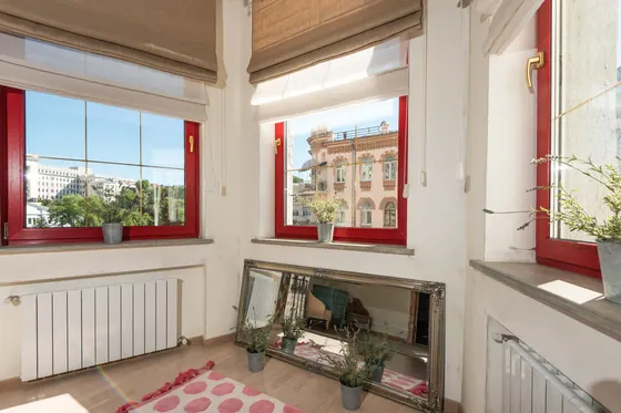 White column radiators beneath red-framed windows