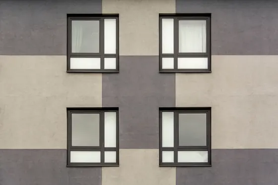 Dark grey window frames on a rendered wall
